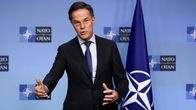 Mark Rutte elehtii käsillään, taustalla Naton lippu.