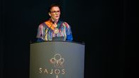 Heidi Eriksen puhuu avajaistervehdystä puhujanpöntössä Saamen mielenterveyskonferenssissa 19. syyskuuta 2025 Sajoksen auditoriossa. Yllään hänellä on saamenpuku.