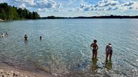 Laaja kuva merenrannasta, jossa kaksi nuorta naista on kahlaamassa etualalla.