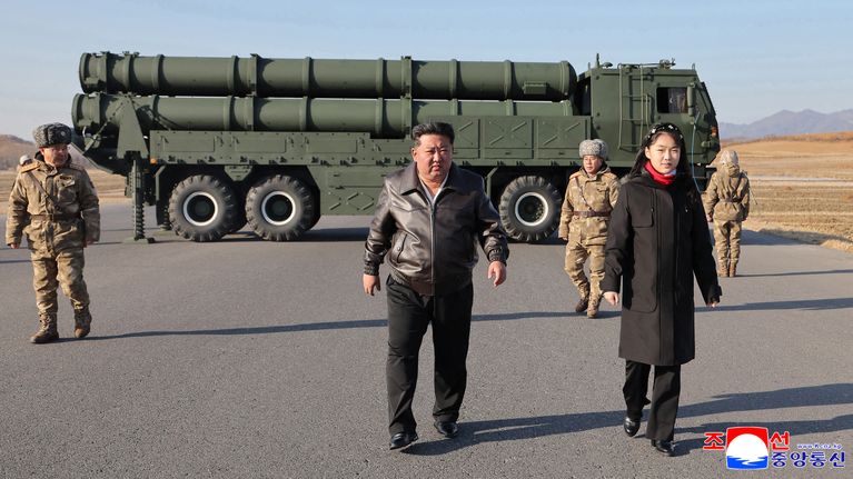 Kim Jong-Un ja hänen tyttärensä Kim Ju Ae kävelevät kohti kameraa. Taustalla raketinheitinauto ja sotilaita.