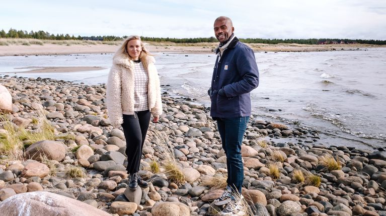 Emilia Hernesniemi ja Jani Toivola seisovat Hailuodossa meren rannalla ja katsovat hymyillen kameraan.