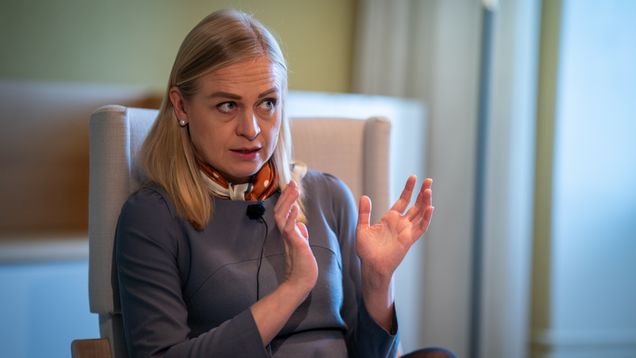 A blonde woman sits in a chair for an interview.