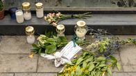 Makeshift memorial with about half a dozen candles, flowers and a card.