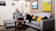 Jarmo ja Tuula Mörö Luna-koiran kanssa harmaalla sohvalla.