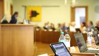 Porin kaupunginvaltuuston kokouksessa valtuutetut istuvat salissa, pöydillä on pulloja ja läppäreitä.