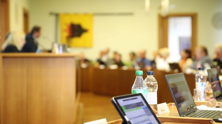 Porin kaupunginvaltuuston kokouksessa valtuutetut istuvat salissa, pöydillä on pulloja ja läppäreitä.