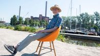Ydinvoiman mallinnuksen professori Juhani Hyvärinen istuu oranssilla tuolilla Hanasaaren voimalan edustalla.