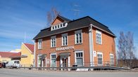 Vinhan kirjakauppa Ruoveden keskustassa. Kirjakaupan rakennus on puinen ja oranssi. Aurinko paistaa ja taivas on sininen.