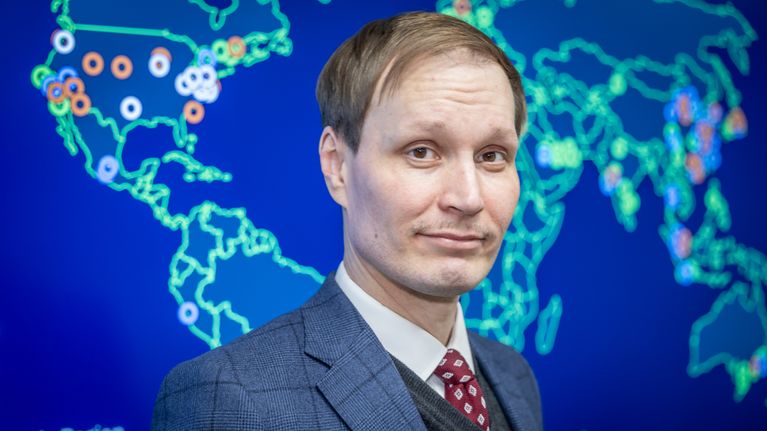 Vili Lehdonvirta seisoo maailmankartan edessä.