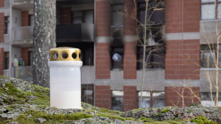 Vantaan pähkinärinteen tulipalossa vaurioitunut talo. Kuvan etualalla muistokynttilä.