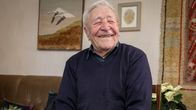 Viljo Pastila istuu olohuoneessa, jossa on kotoinen sisustus. 
