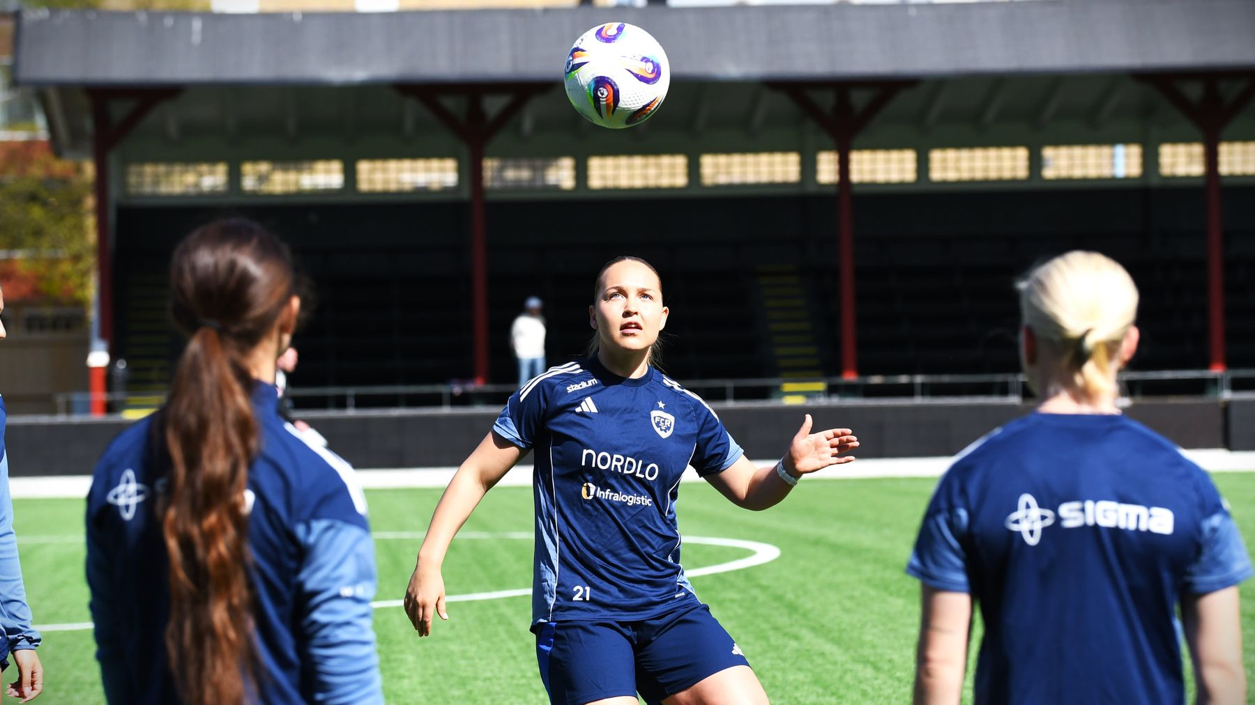 Oona Sevenius trixar med bollen på solig fotbollsplan.
