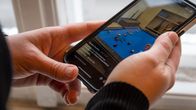 En anonym person håller i en mobiltelefon och tittar på en video.