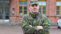 En man i militärkläder framför en kasern.