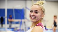 Voimistelija Kaia Tanskanen hymyilee kameralle voimistelusalissa.