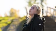 Peppi Konsteri sitter vid vattnet och tittar upp mot himlen.