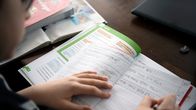 Alakoululainen tekee matematiikan tehtäviä kotonaan.