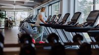Nainen juoksumatolla kuntosalilla.