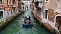 En båt i en kanal i Venedig, mellan två tegelstensbyggnader.