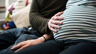 Raskaan oleva henkilö kumppaninsa kanssa sohvalla.