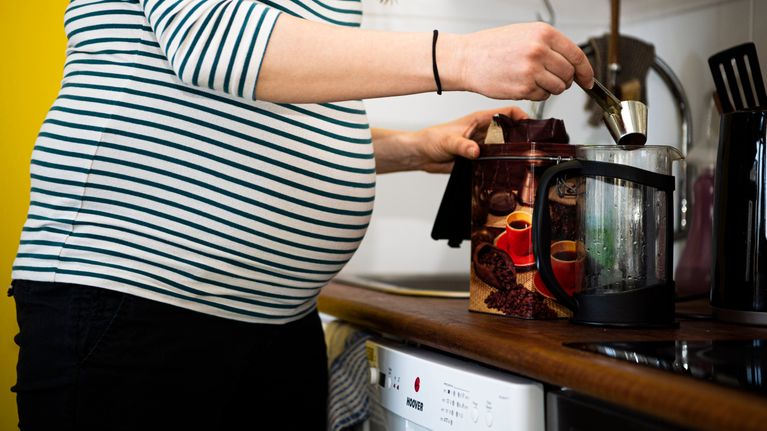 En gravid person kokar kaffe.