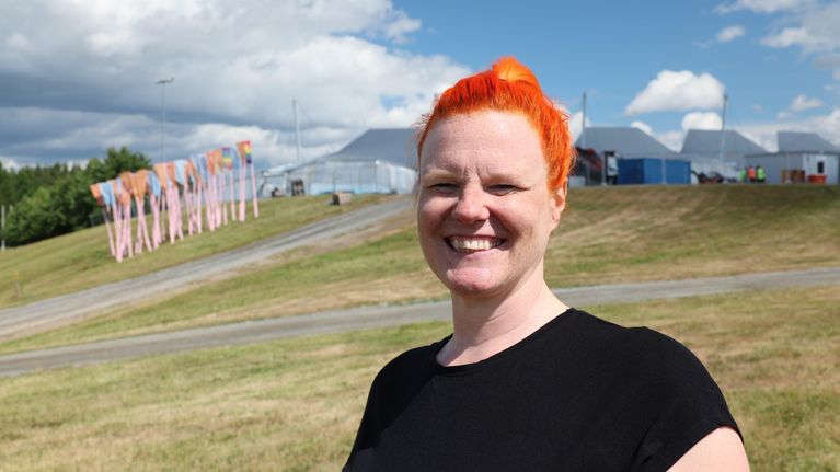 Ilosaarirockin oranssitukkainen tuotantopäällikkö Katri Kilpiä Joensuun laululavan takarinteellä aurikoisena kesäpäivänä.
