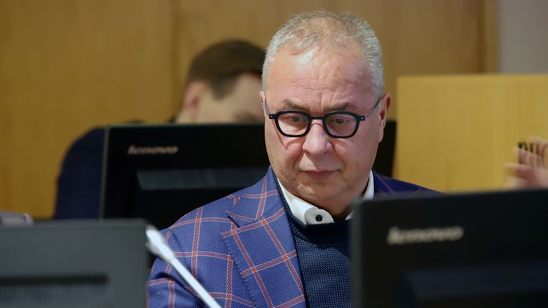 En person i rutig kavaj sitter vid ett skrivbord med flera datorer.