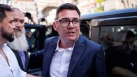 Andy Burnham tummassa pikkutakissa nousee mustasta autosta.