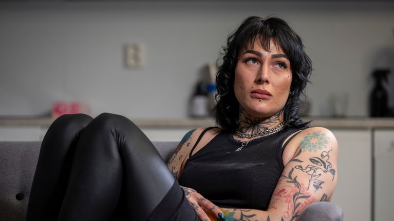 Henrietta Palmi istuu sohvalla ja pitelee käsiä vatsan päällä.