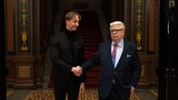 Kalervo Kummola ja Ilmari Nurminen kättelevät. Kummola katsoo kameraan.