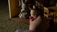 Sylvanian family -lelutalo ja pupuhahmoja. Lapsen käsi leikkimässä leluilla.