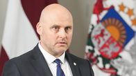 Mies Latvian kansallissymboleiden edessä.
