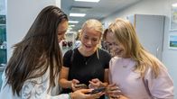 Tre skolungdomar tittar på varandras mobiltelefoner i Mattliden skola i Esbo.