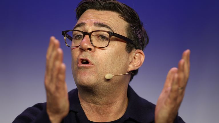 Poliitikko Andy Burnham pitää puhetta tilaisuudessa. Hänellä on leuan alle kiinnitetty pieni mikrofoni.