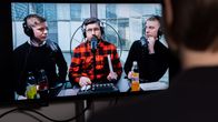 Anonyymi henkilö katsomassa tietokoneelta Youtuben vodcastia. Ruudulla kolme kansanedustajaa.