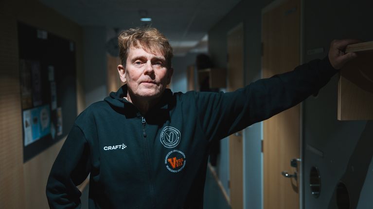 En person står i en korridor med ena armen lutad mot en hylla.