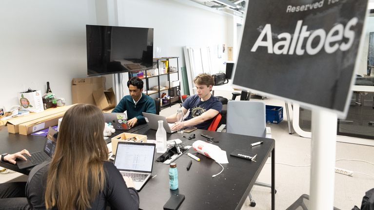 Ayaan Jamil palaverissa muiden opiskelijoiden kanssa. Etualalla kyltti "reserved for Aaltoes".