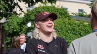 Wilma Heltelä, en person med ljust hår och keps, står utomhus och samtalar med en annan person.