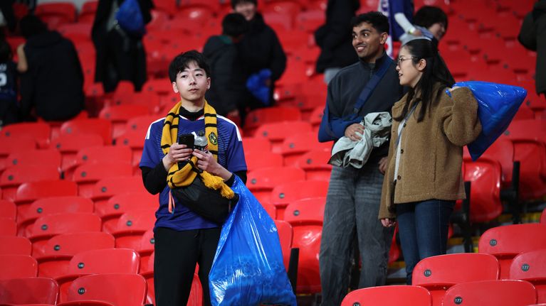 Japanilaisia faneja jalkapallokatsomossa roskasäkkien kanssa.