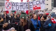 Demonstranter marscherar med en banderoll som lyder "WE SHAPE OUR FUTURE" och grönländska flaggor.