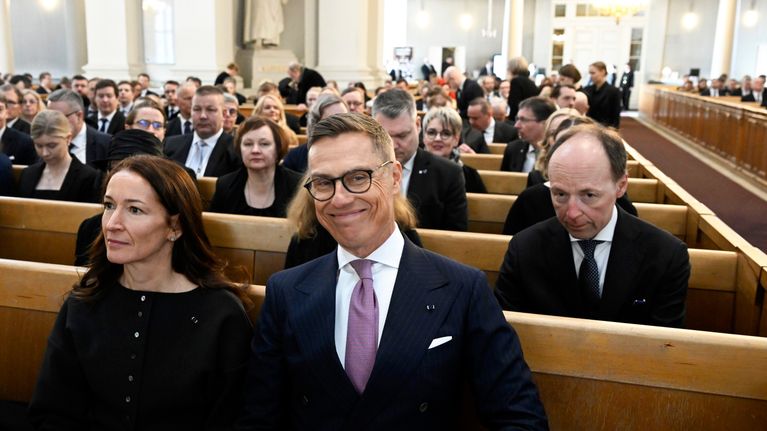 Suzanne Innes-Stubb, Alexander Stubb ja  Jussi Halla-aho istuvat jumalanpalveluksessa kirkossa.