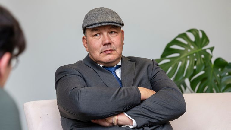 Juha Mäenpää istuu penkillä kädet puuskassa.