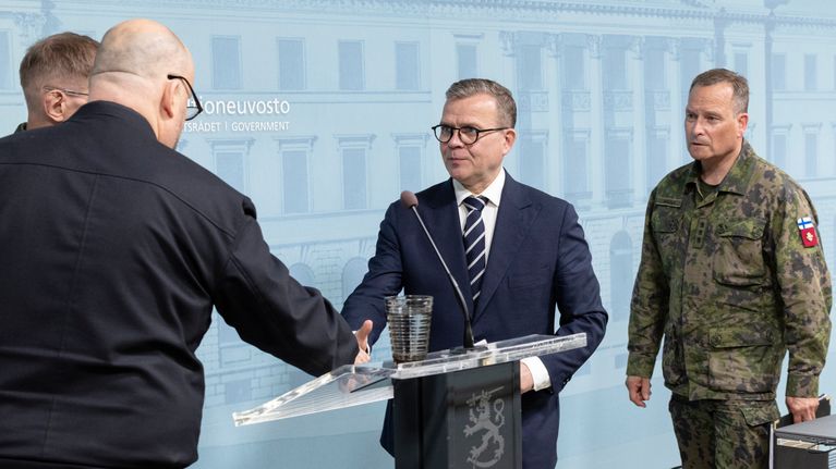 Pääministeri Petteri Orpo kättelee toista miestä.