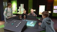 Opettaja ja kolme alakoulun oppilasta pelaavat tietovisa-peliä tiedekeskus Pilkkeessä.