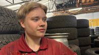Rengasliikkeen työntekijä työskentelee varastossa, jossa on pinottuja autonrenkaita.
