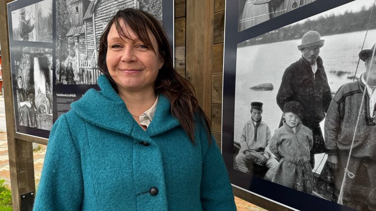Anne-Marie Kalla katsoo suoraan kameraan taulujen edessä.