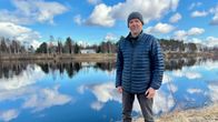 Mies seisoo joen törmällä, taustalla pilviä heijastava Ivalojoki. 