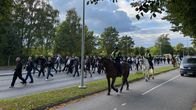 Ihmiset kävelevät keskellä ajotietä, eräänlaisessa kulkueessa. Ratsupoliisit ja poliisi seuraavat kulkuetta.