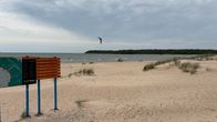 Yyterin hiekkaranta. Leijalautailija meressä. Lainelauta vielä hiekalla.