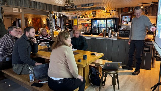 Ihmiset kuuntelevat tarkoin Jaakko Erkinaroa Näätämöjoen tilanteesta Sevettijärven baarissa.